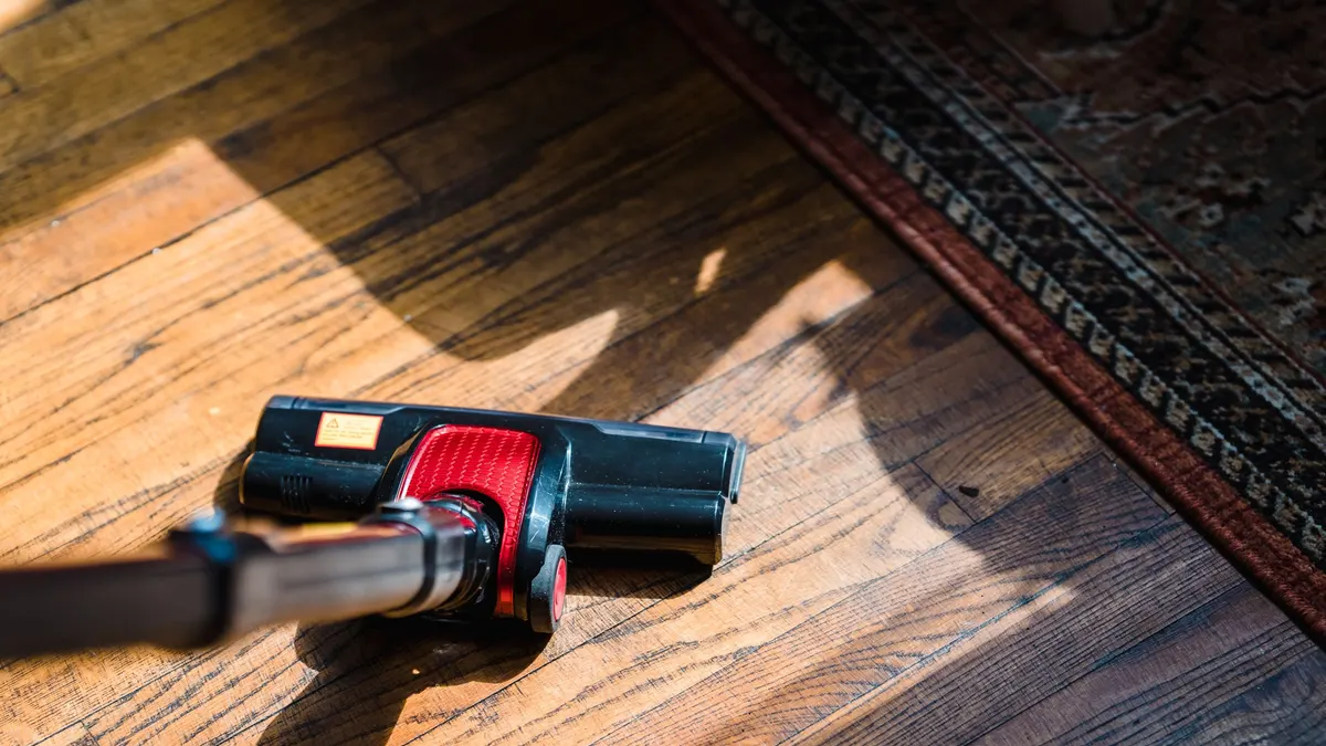 Vacuum nozzle on a wooden floor near a rug