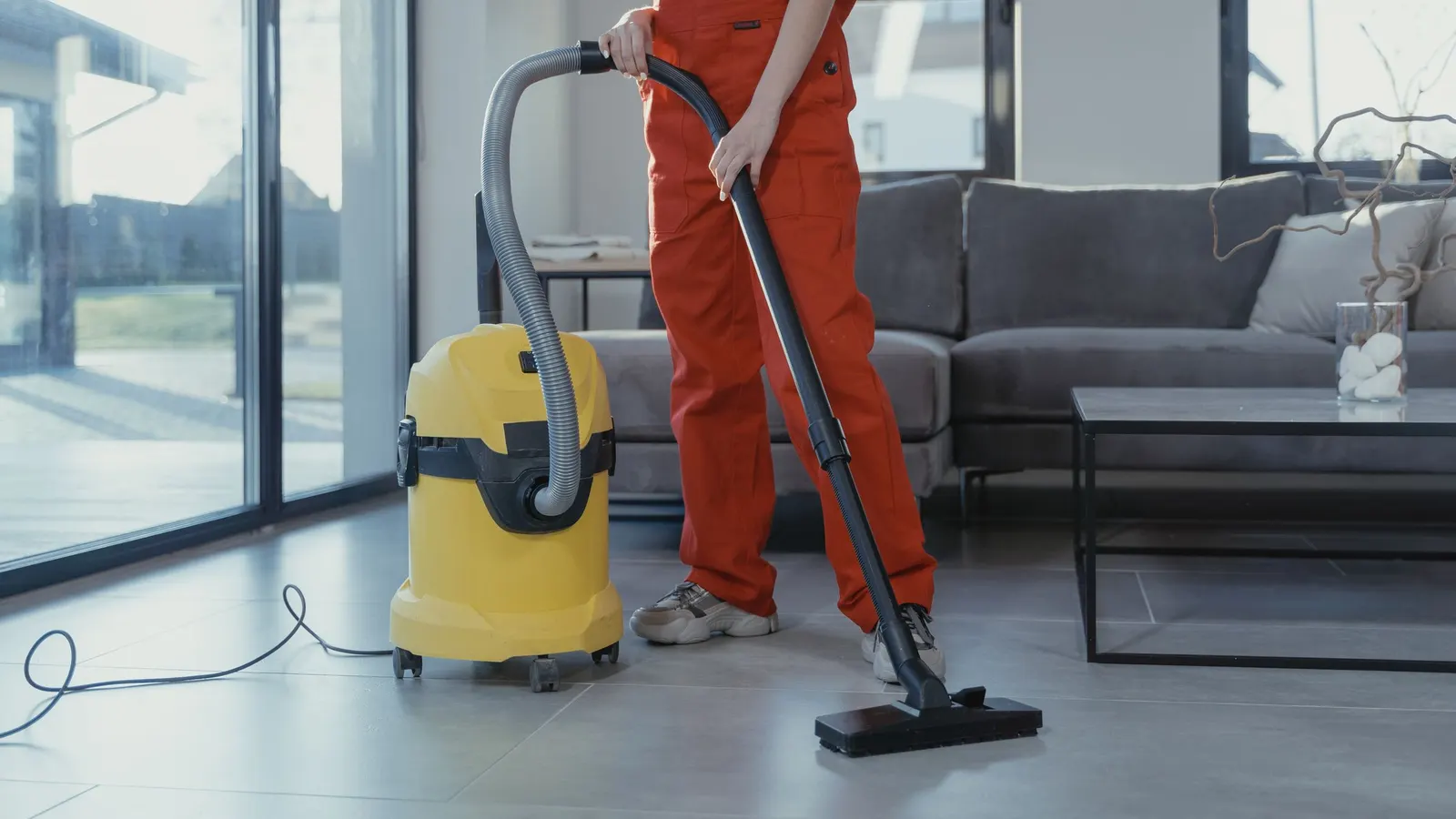 Person cleaning with a yellow wet and dry shop vac